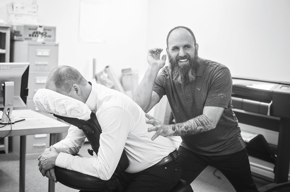 Hands-on chair massage and stretching session in a corporate office