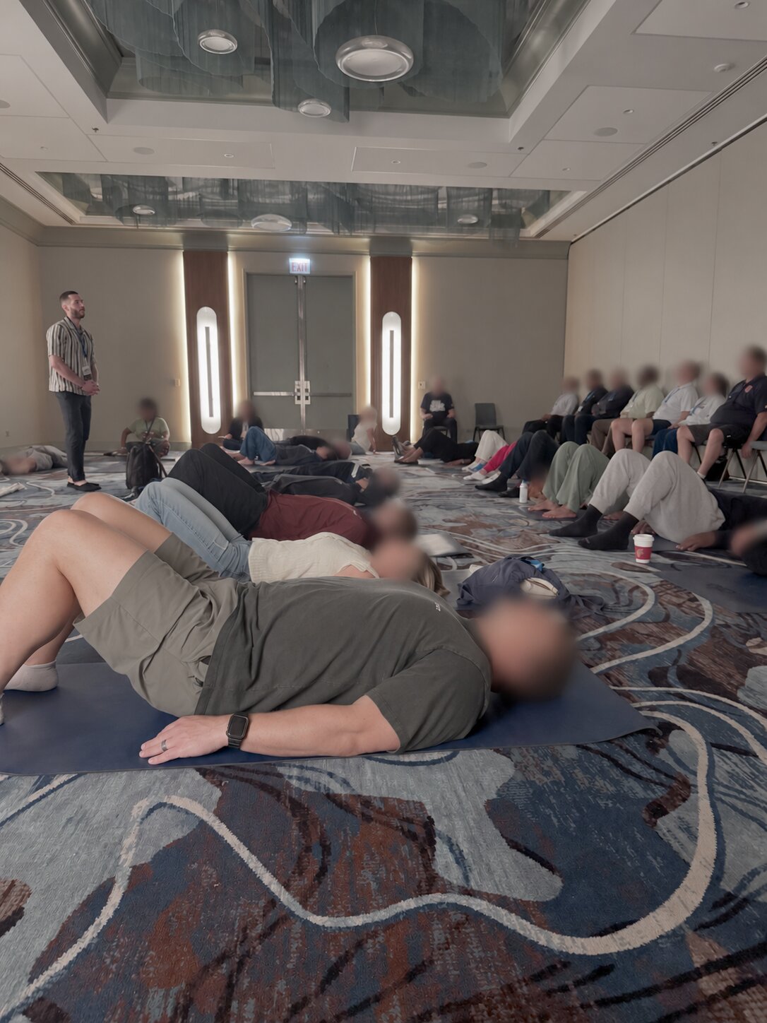 Large group lying on mats during a wellness activation, faces blurred for privacy